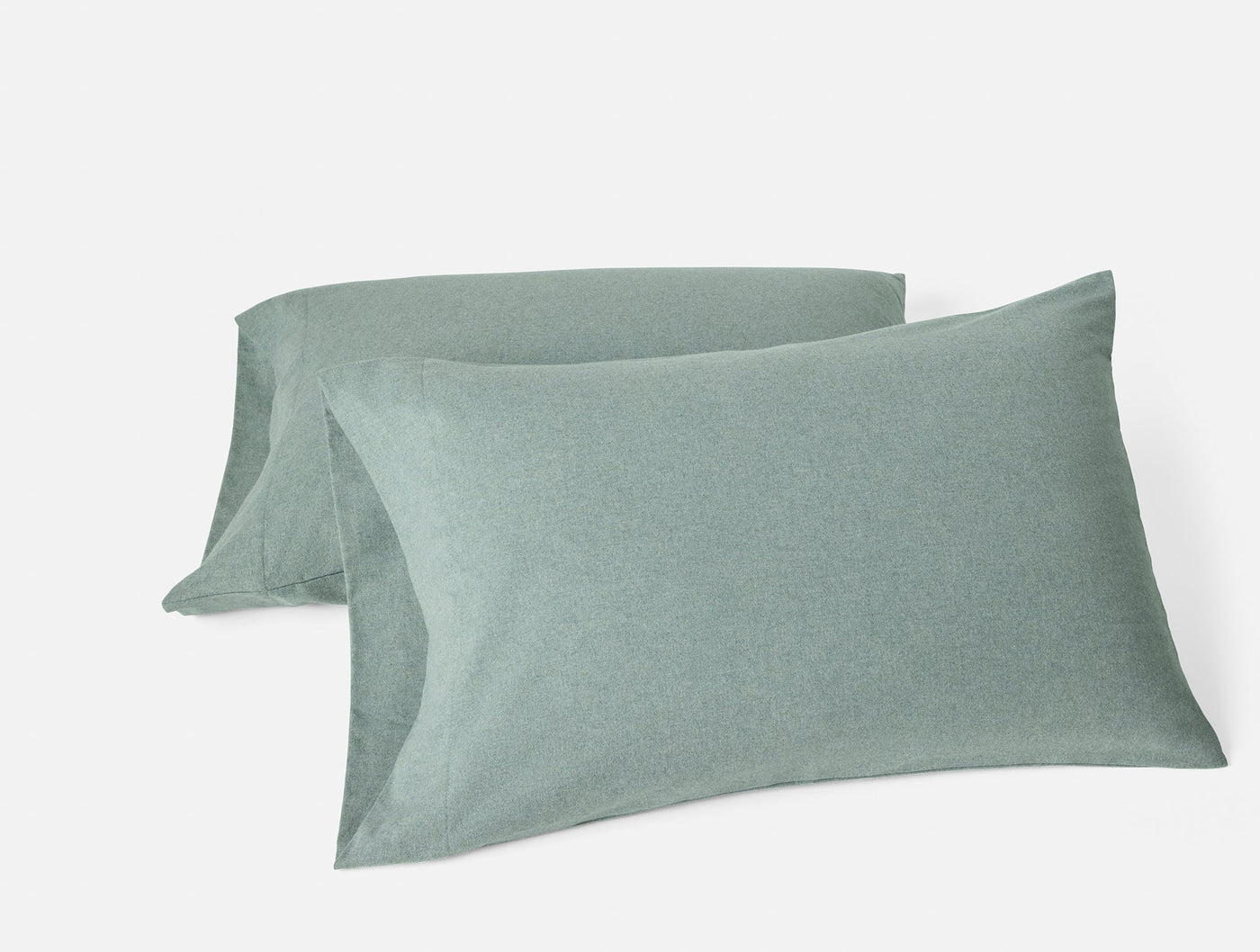 Pair of sage green brushed flannel pillowcases stacked against white background.