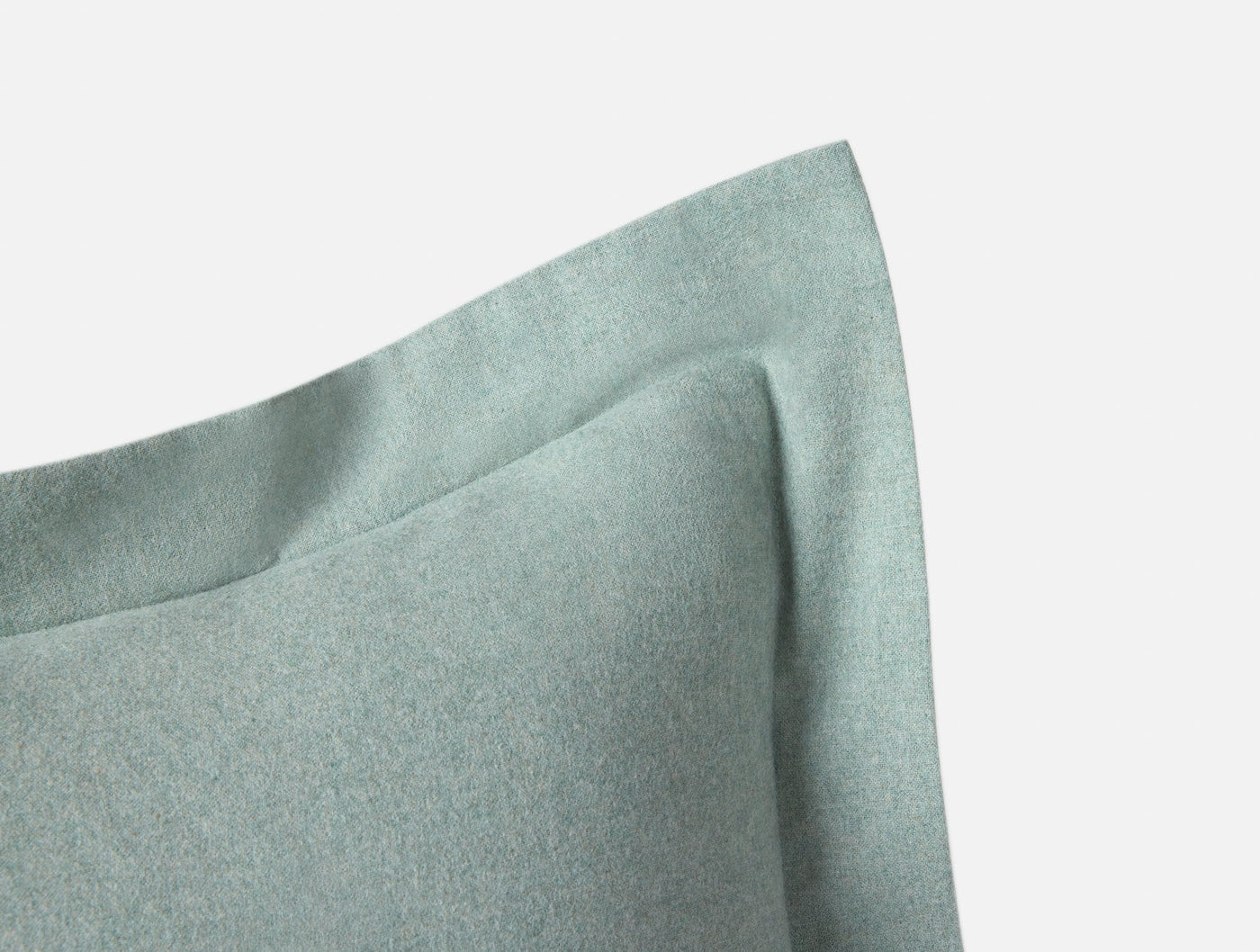 Close-up of sage green flannel pillow sham corner, showing brushed texture and flange edge detail.