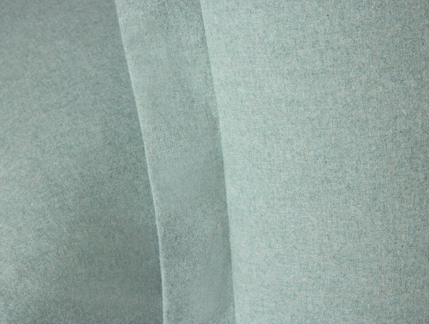 Close-up of sage green brushed flannel fabric with soft, draped folds.