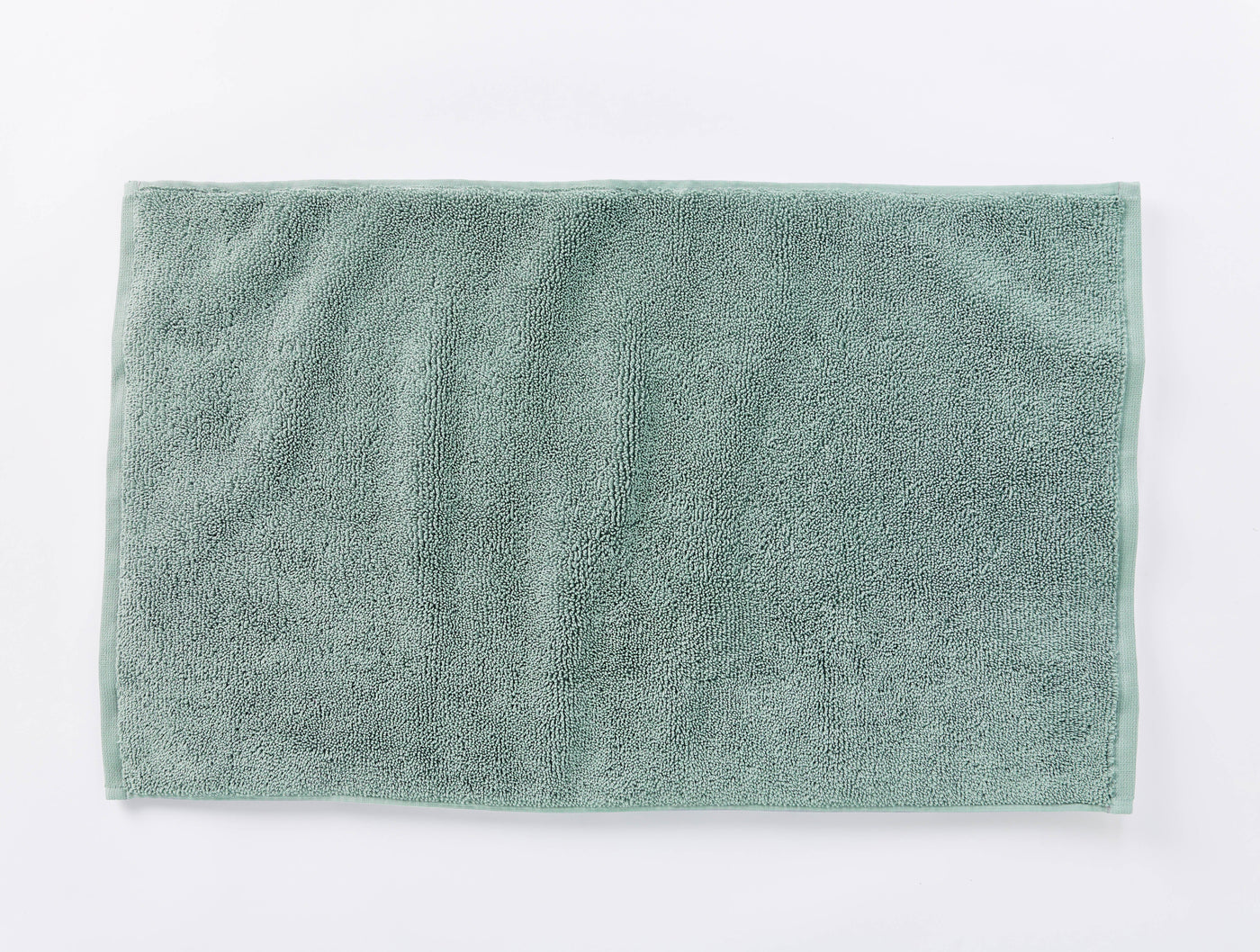 Coyuchi Cloud Loom bath rug in sage green, flat lay showing plush terry texture.