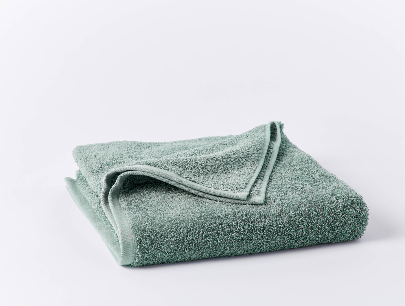 Coyuchi Cloud Loom hand towel folded, sage green terry cloth, corner turned back.