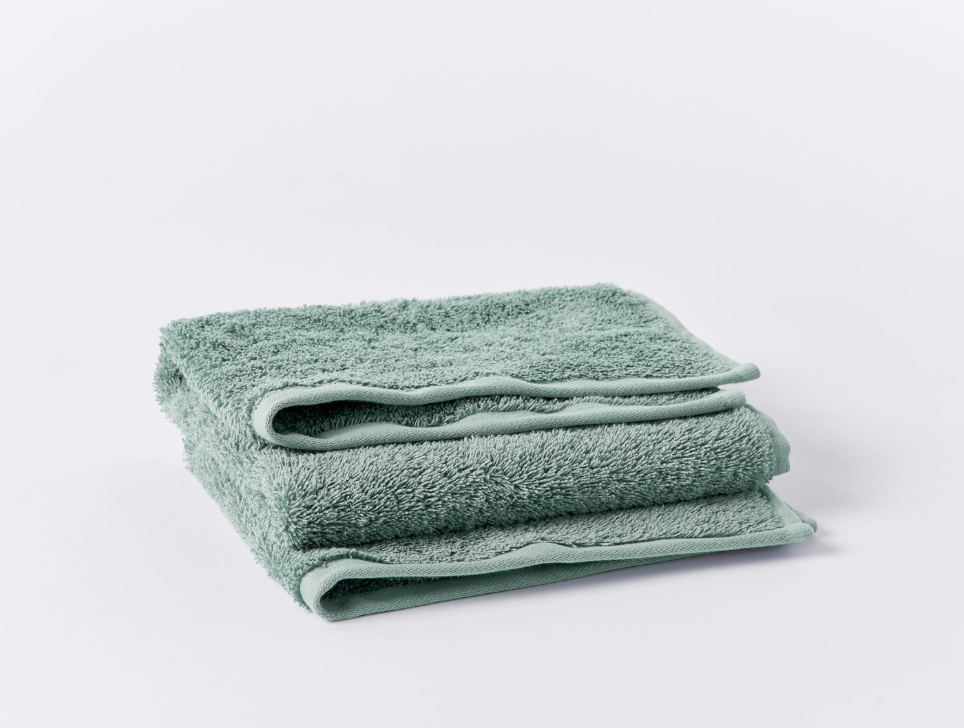 Close-up of folded sage green Coyuchi Cloud Loom bath sheet showing plush terry texture.