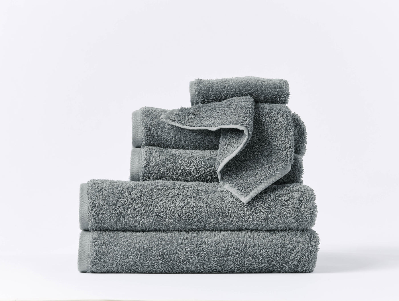 Stacked slate Coyuchi Cloud Loom towel set showing varied sizes on white background.