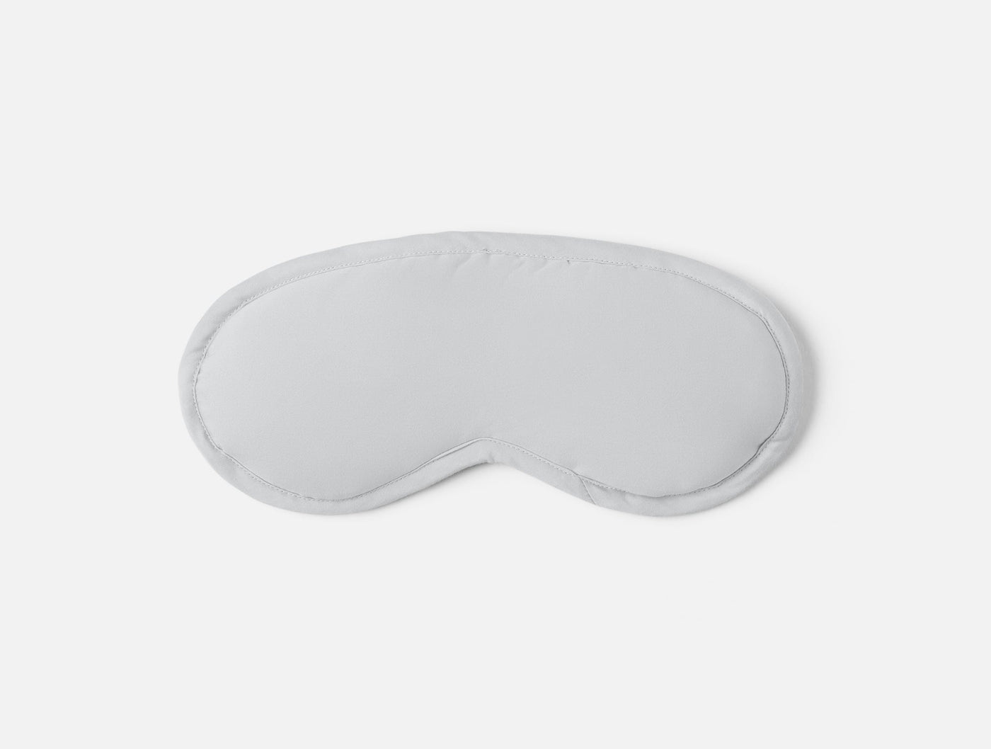 Flat lay of a white sateen eye mask with piped trim detail.