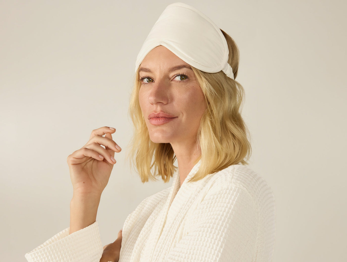 Ivory sateen eye mask worn on model's head as headband, paired with white waffle robe.