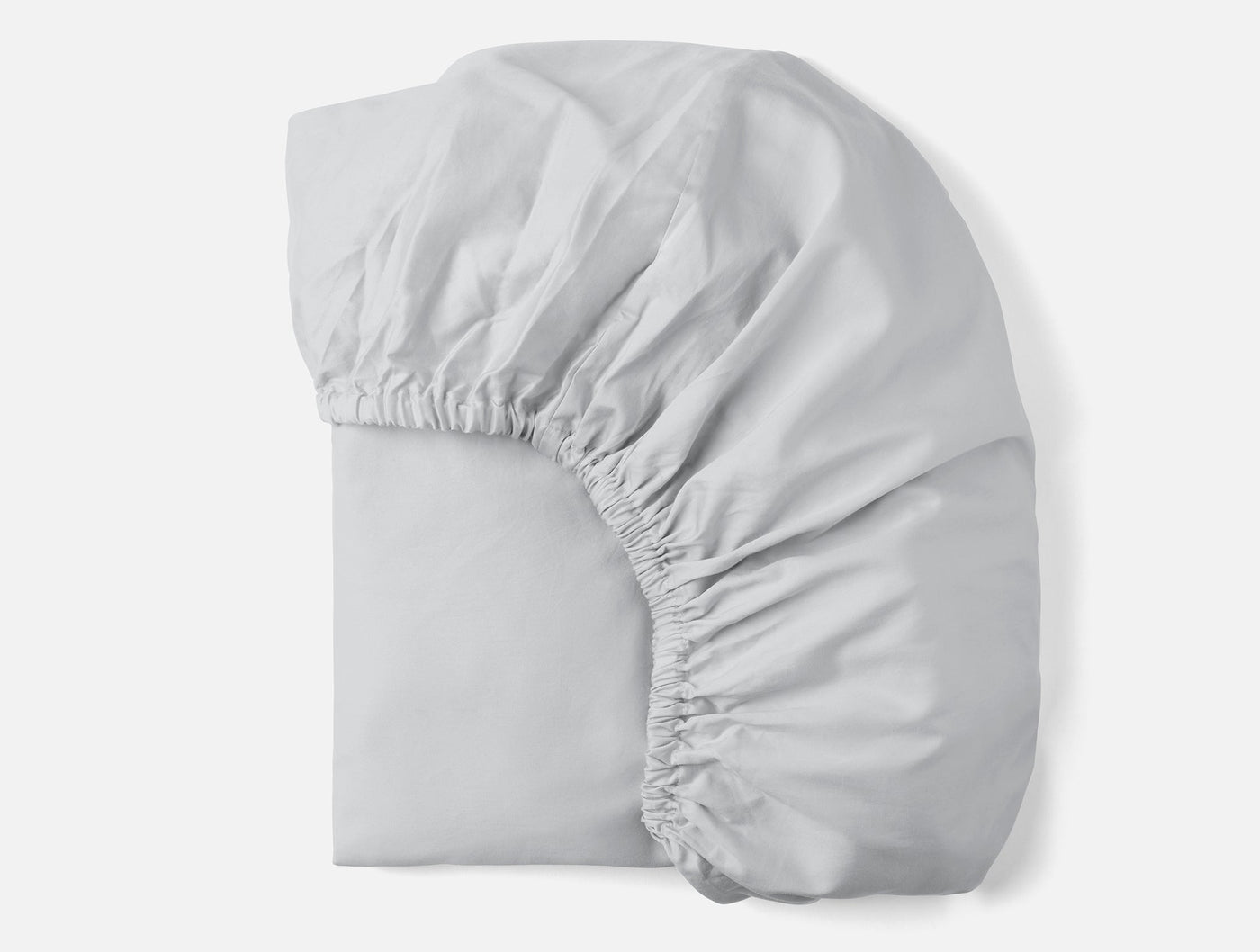 Coyuchi Cloud Soft Sateen fitted sheet folded, silver white with visible elasticized corners.