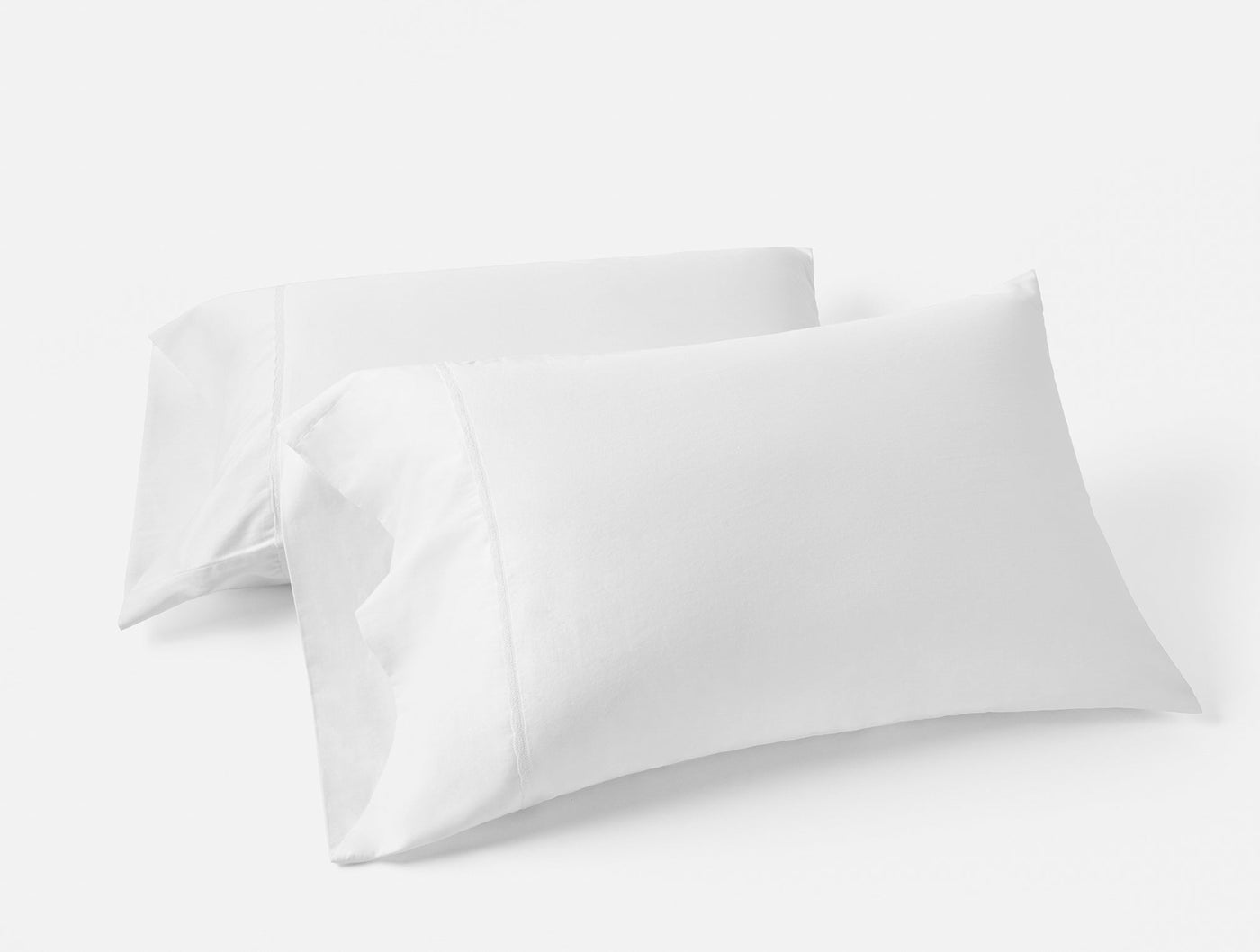Two white Coyuchi Cloud Soft Sateen pillowcases stacked, showing crisp envelope closure detail.