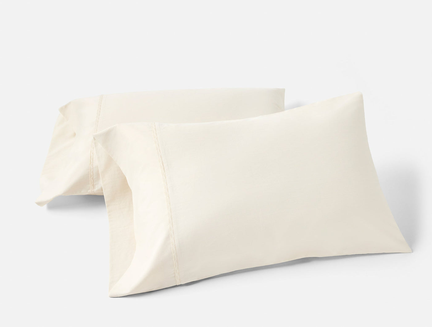 Pair of ivory sateen pillowcases with subtle sheen, stacked against white background.