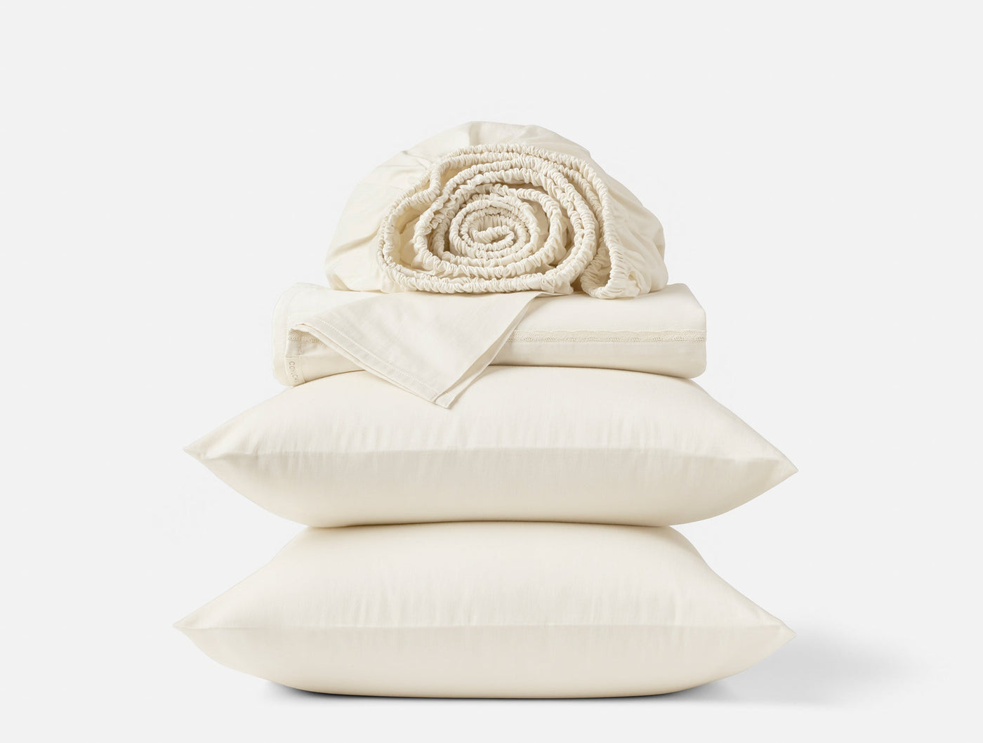 Ivory sateen sheet set stacked with rolled waffle blanket atop two pillowcases.
