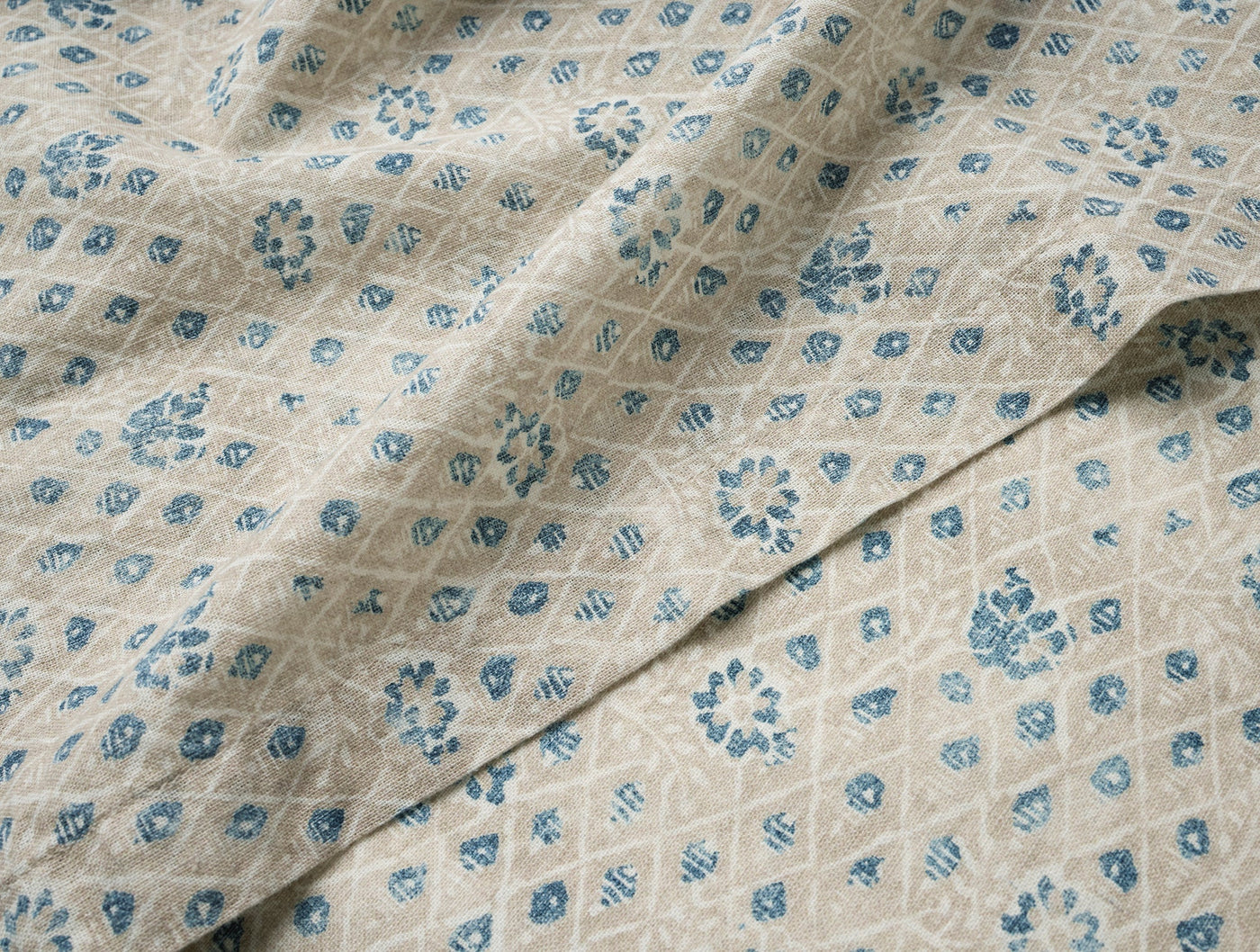 Close-up of Coyuchi Coral Bell Print tablecloth, blue floral diamond pattern on natural linen.