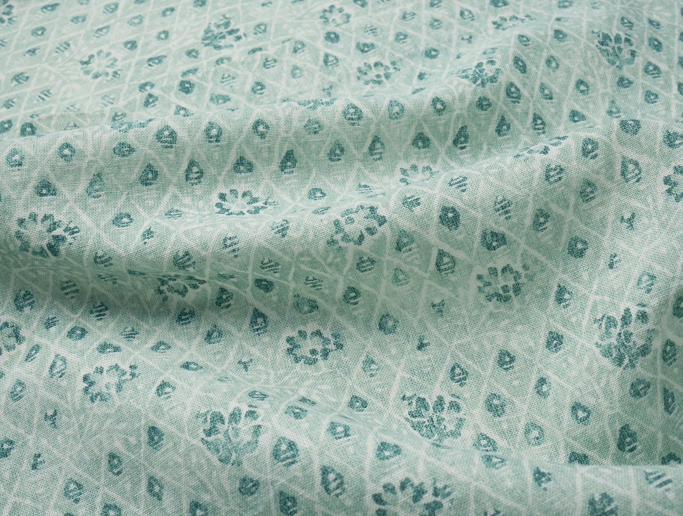 Close-up of Coyuchi Coral Bell Print napkin in seafoam, showing teal floral and diamond woven pattern.