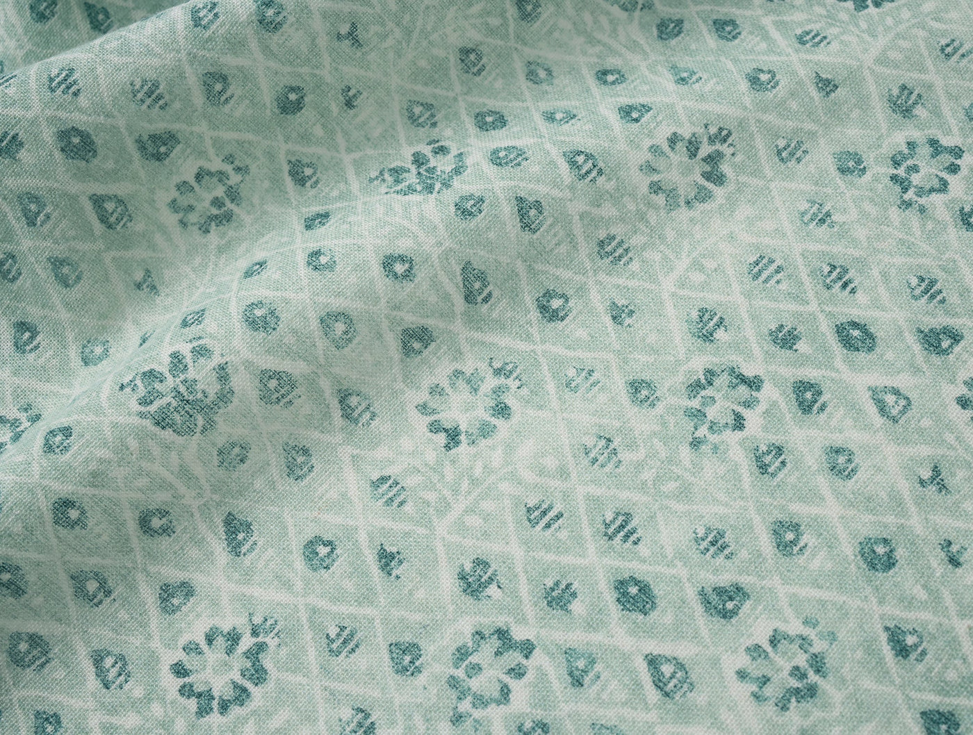 Close-up of Coyuchi Coral Bell Print fabric showing teal floral motifs on seafoam linen.