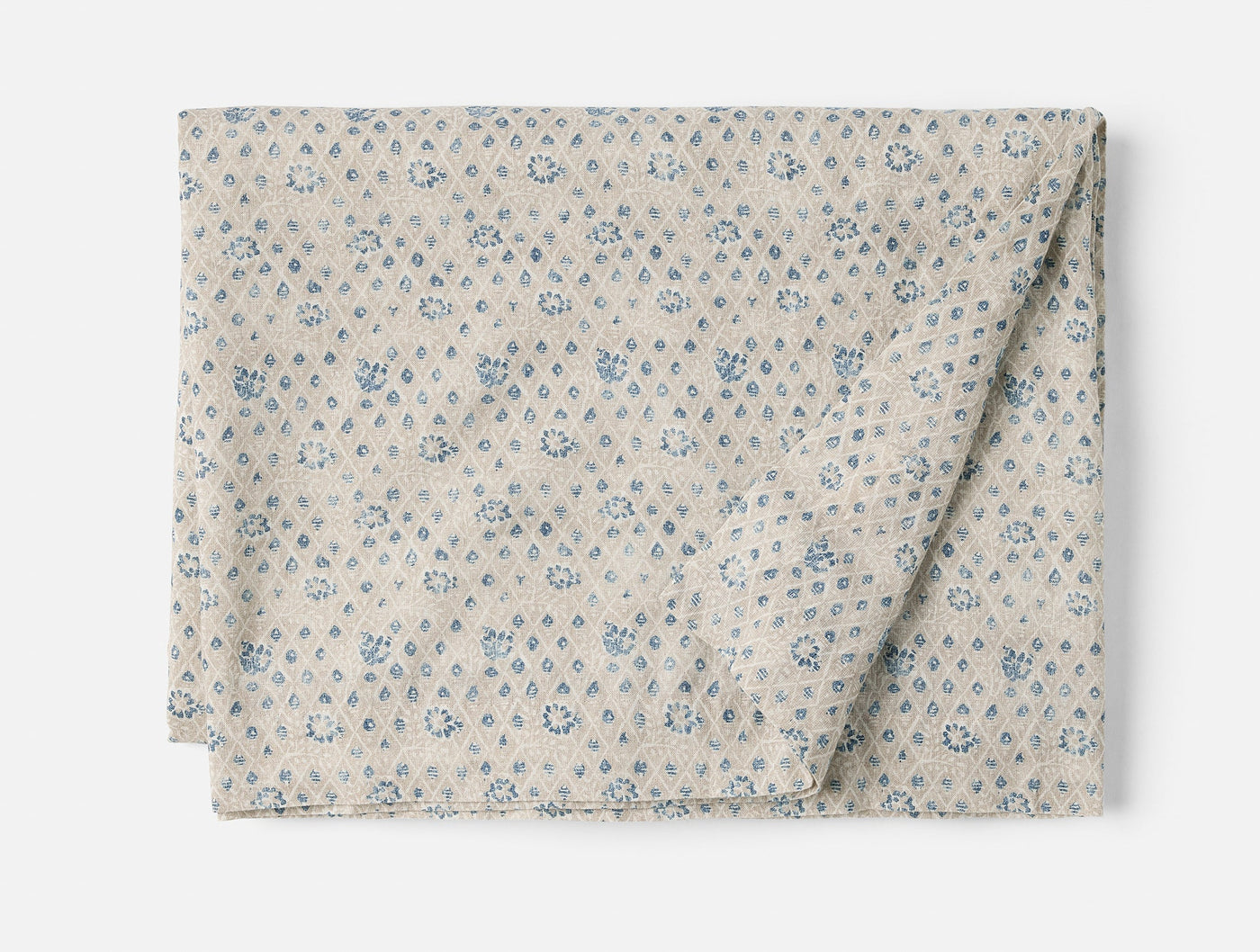 Coyuchi Coral Bell Print tablecloth, folded, oatmeal with blue floral diamond pattern.