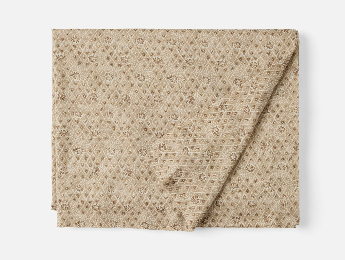 Folded sand tablecloth with allover diamond and floral block-print pattern.
