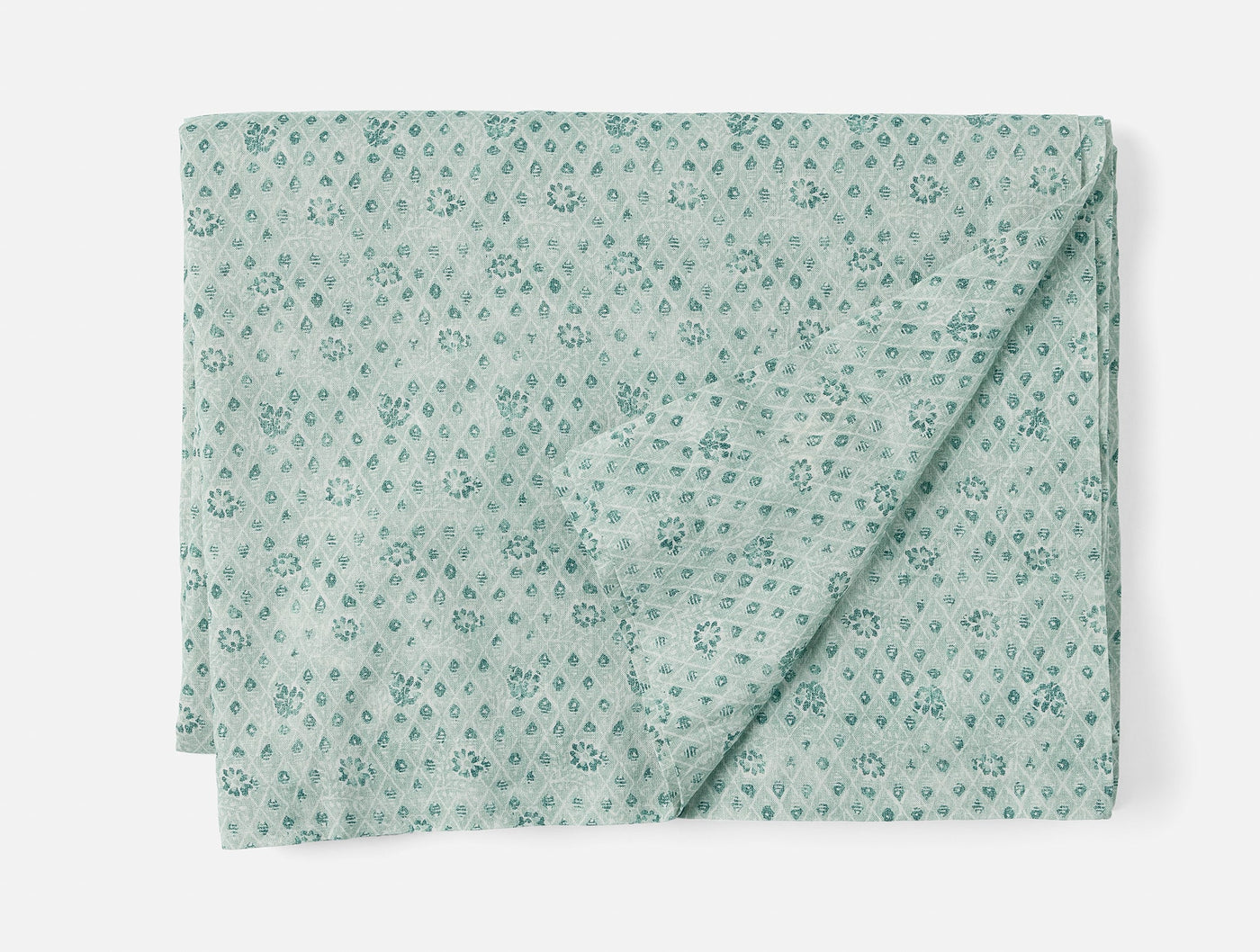 Coyuchi Coral Bell Print tablecloth folded, sage green with tonal floral diamond print.