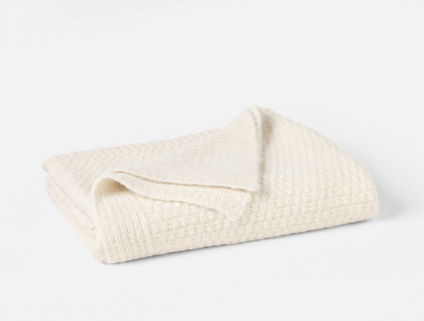 Close-up of ivory alpaca cotton knit throw, folded to show waffle texture detail.