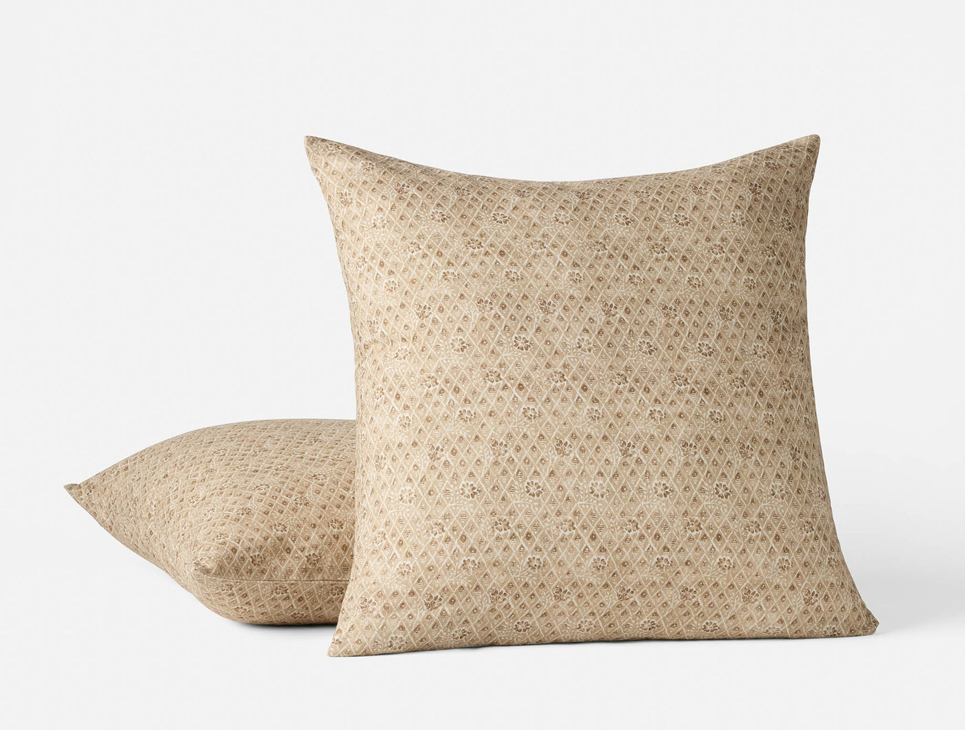 Coyuchi Coral Bell Print pillow covers in sand, small geometric floral repeat pattern, two sizes stacked.