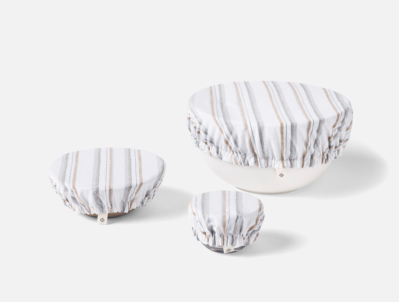 Three Coyuchi Conserve bowl covers in varied sizes, grey and tan stripe linen.