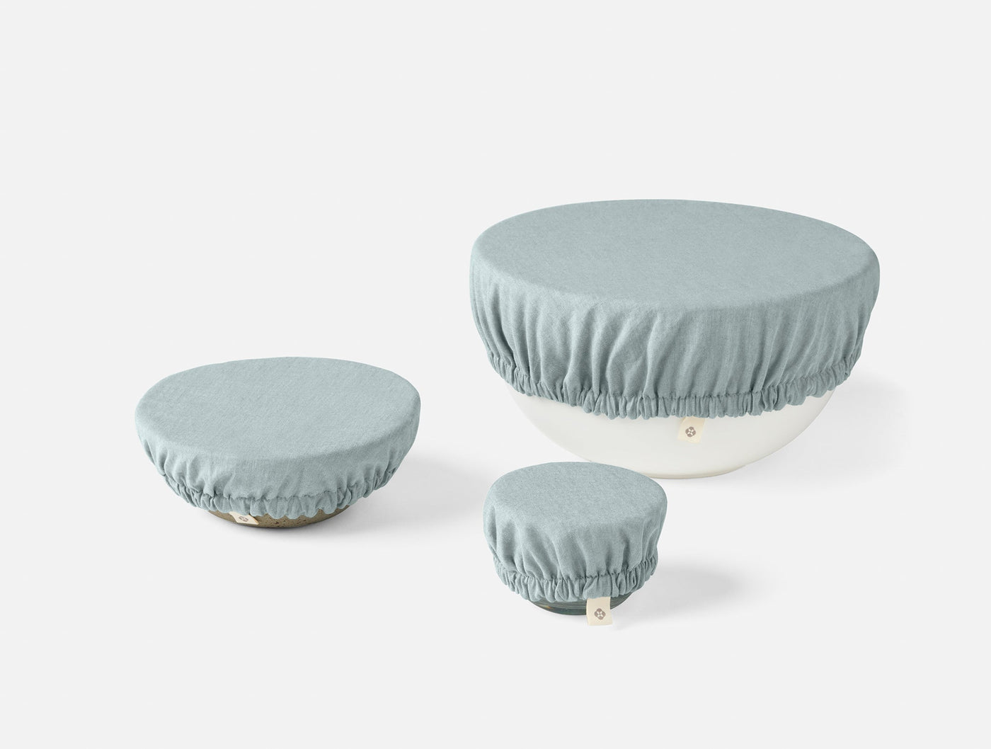 Three Coyuchi Conserve bowl covers in mist blue, shown in small, medium, and large sizes.