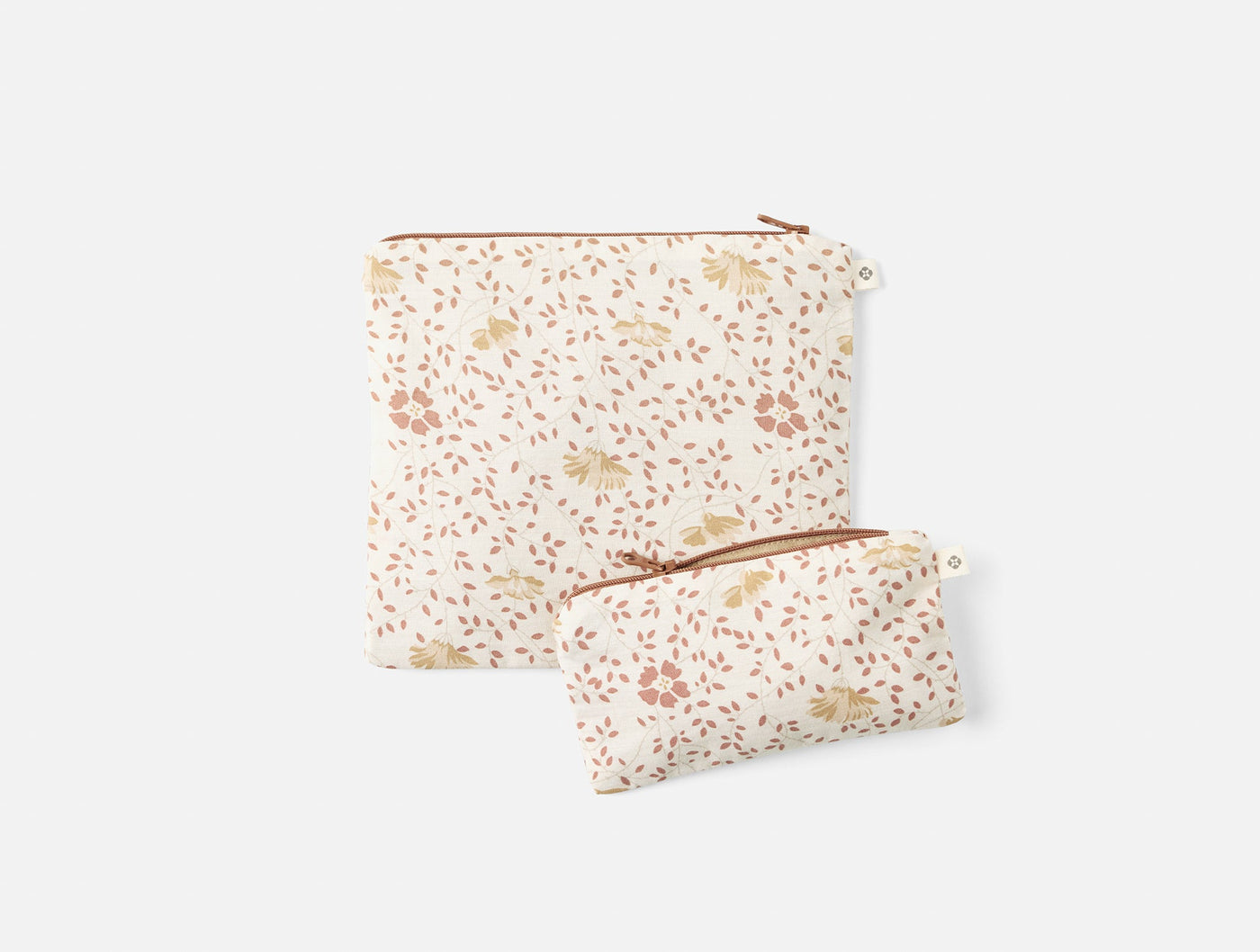 Two Coyuchi Conserve snack bags in ivory floral print with rust zipper pulls, large and small sizes.