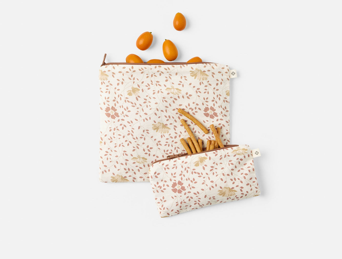 Two Coyuchi Conserve snack bags in floral print, styled with kumquats and breadsticks.