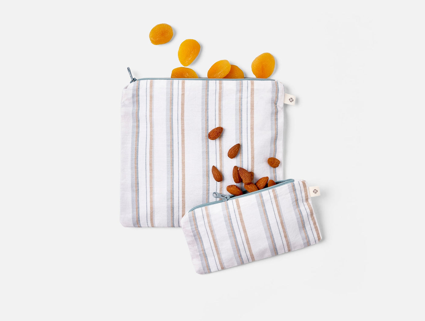Coyuchi Conserve snack bag set styled with dried apricots and almonds spilling out.