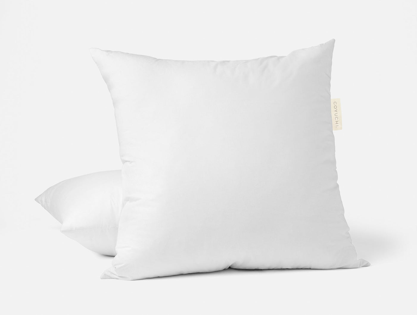 Two white Coyuchi feather/down pillow inserts stacked, showing plump fill and branded label.