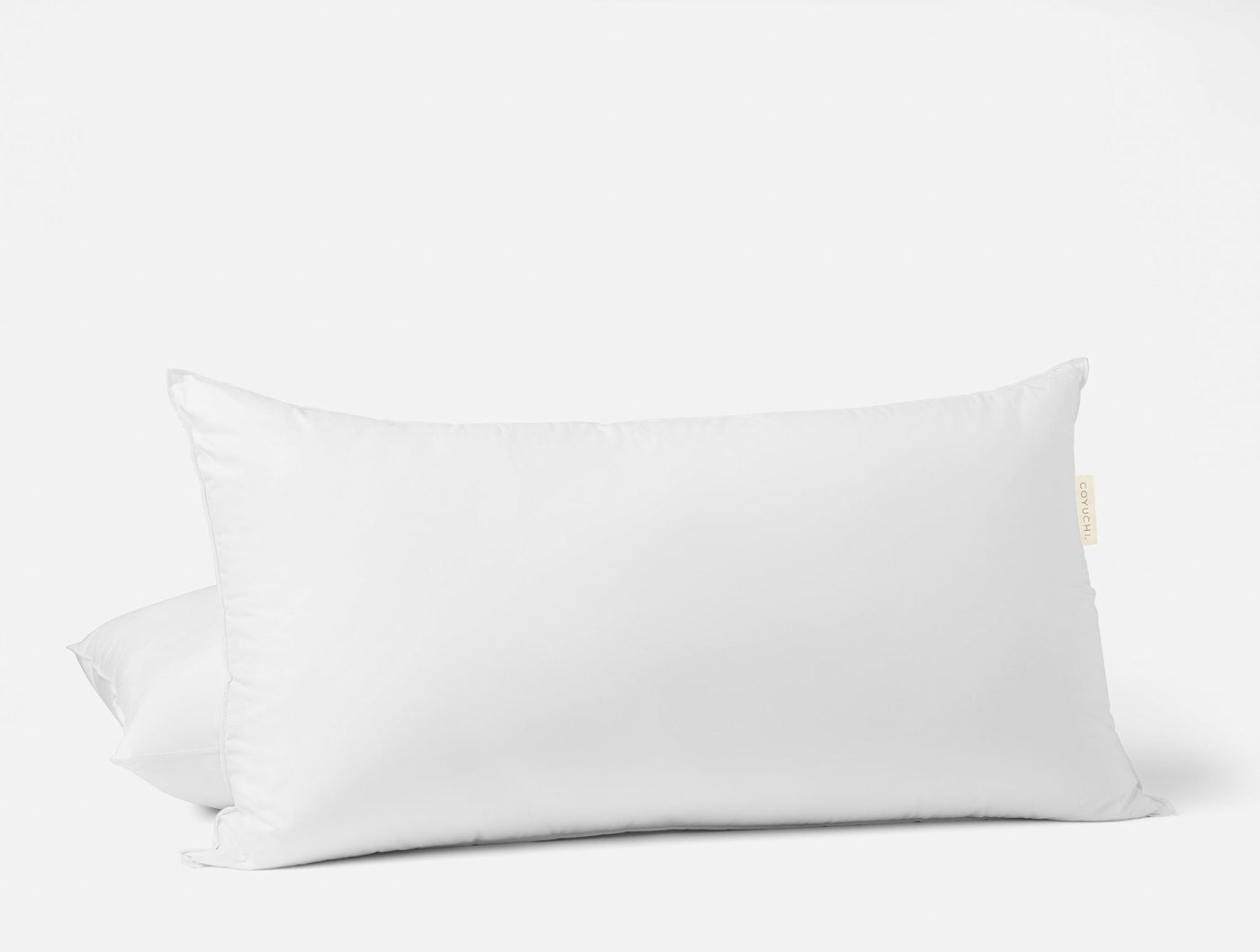 Two white Coyuchi feather down pillow inserts stacked, rectangular bolster shape.