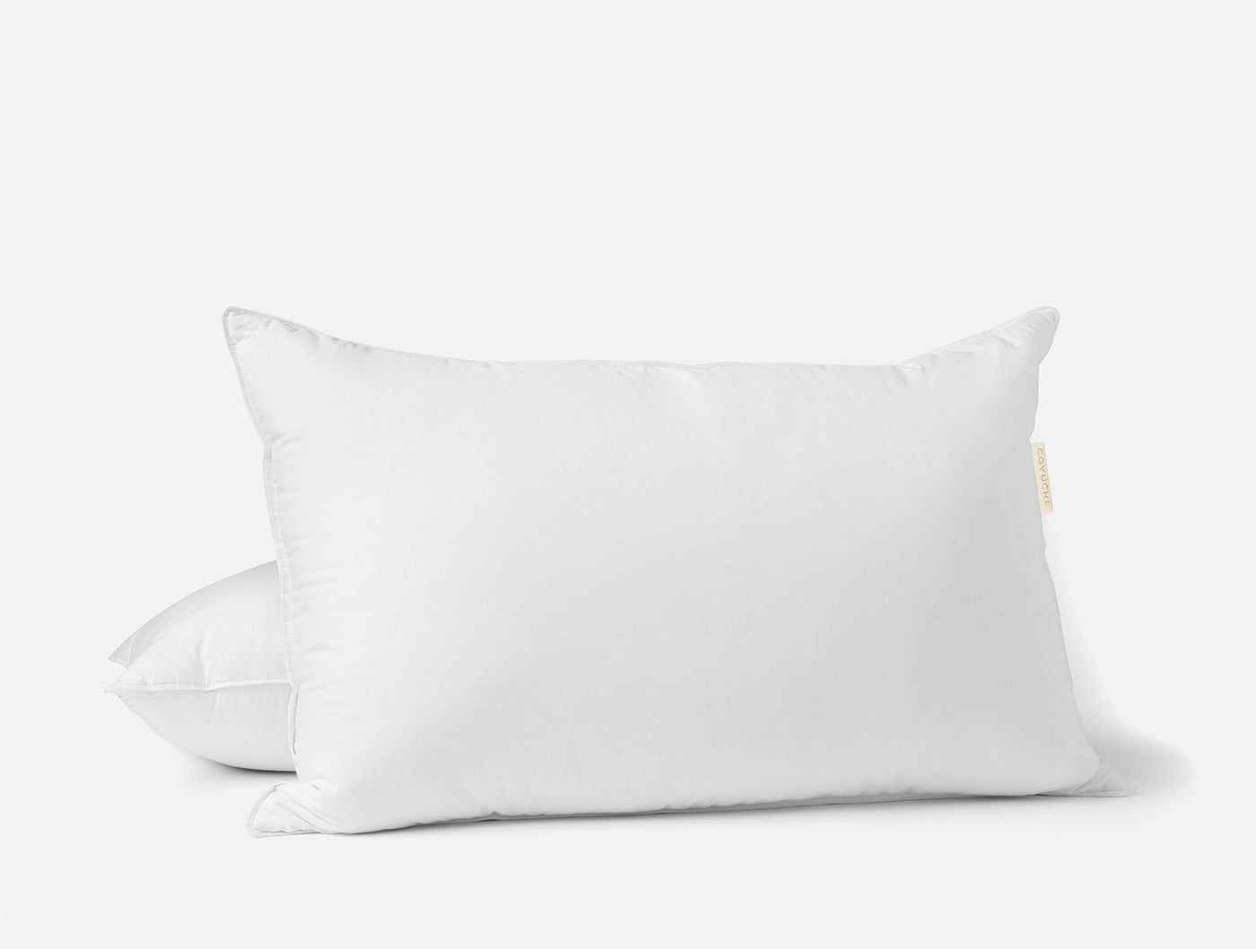 Two white Coyuchi feather/down pillow inserts stacked, king and standard sizes shown together.