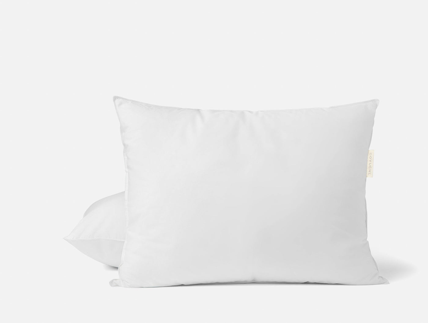 Two white Coyuchi feather/down pillow inserts stacked, small cream label visible on edge.