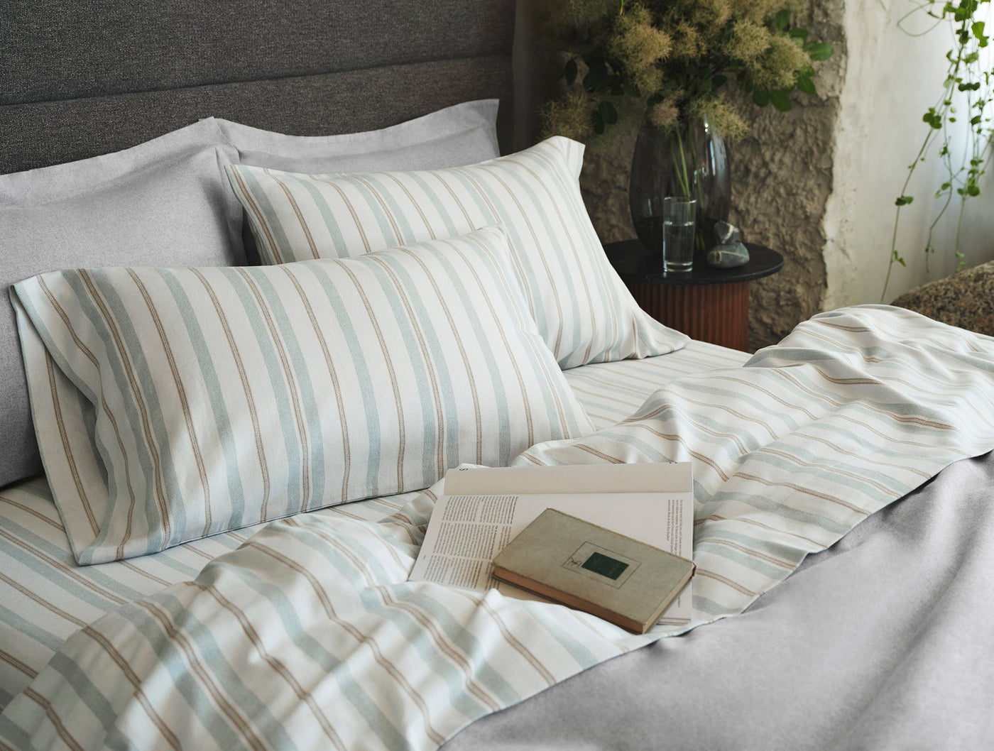 Coyuchi Cloud Brushed Flannel sham in sage and dune stripes, styled on a made bed.