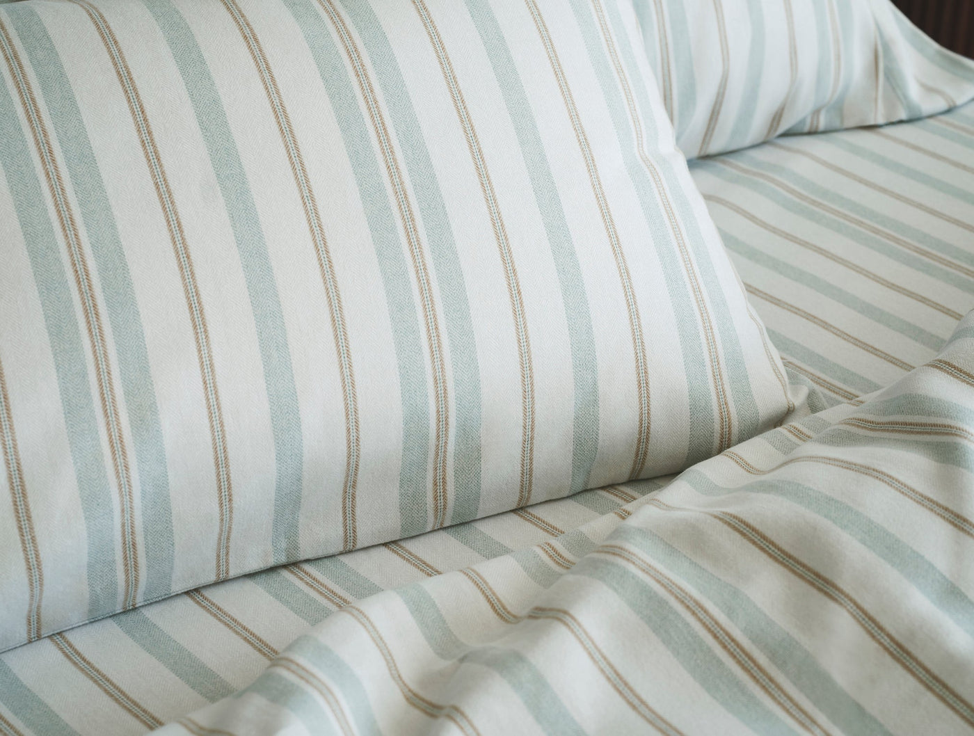 Close-up of Coyuchi Cloud Brushed Flannel pillowcase in seafoam and tan stripe pattern.