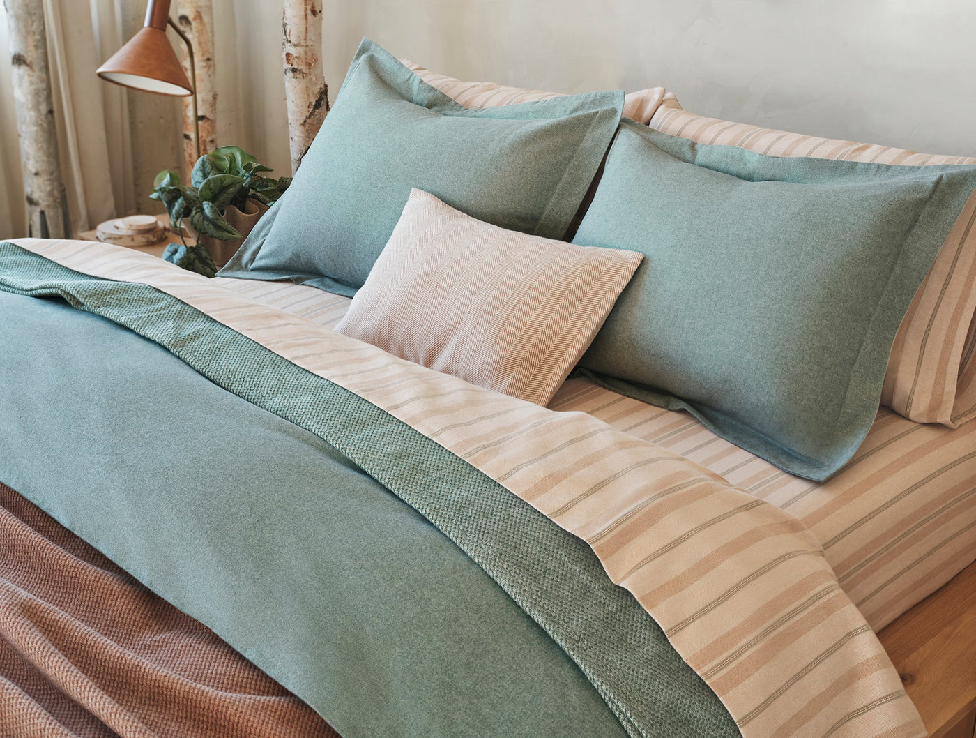 Coyuchi Cloud Brushed Flannel duvet cover in sage green styled on a made bed.