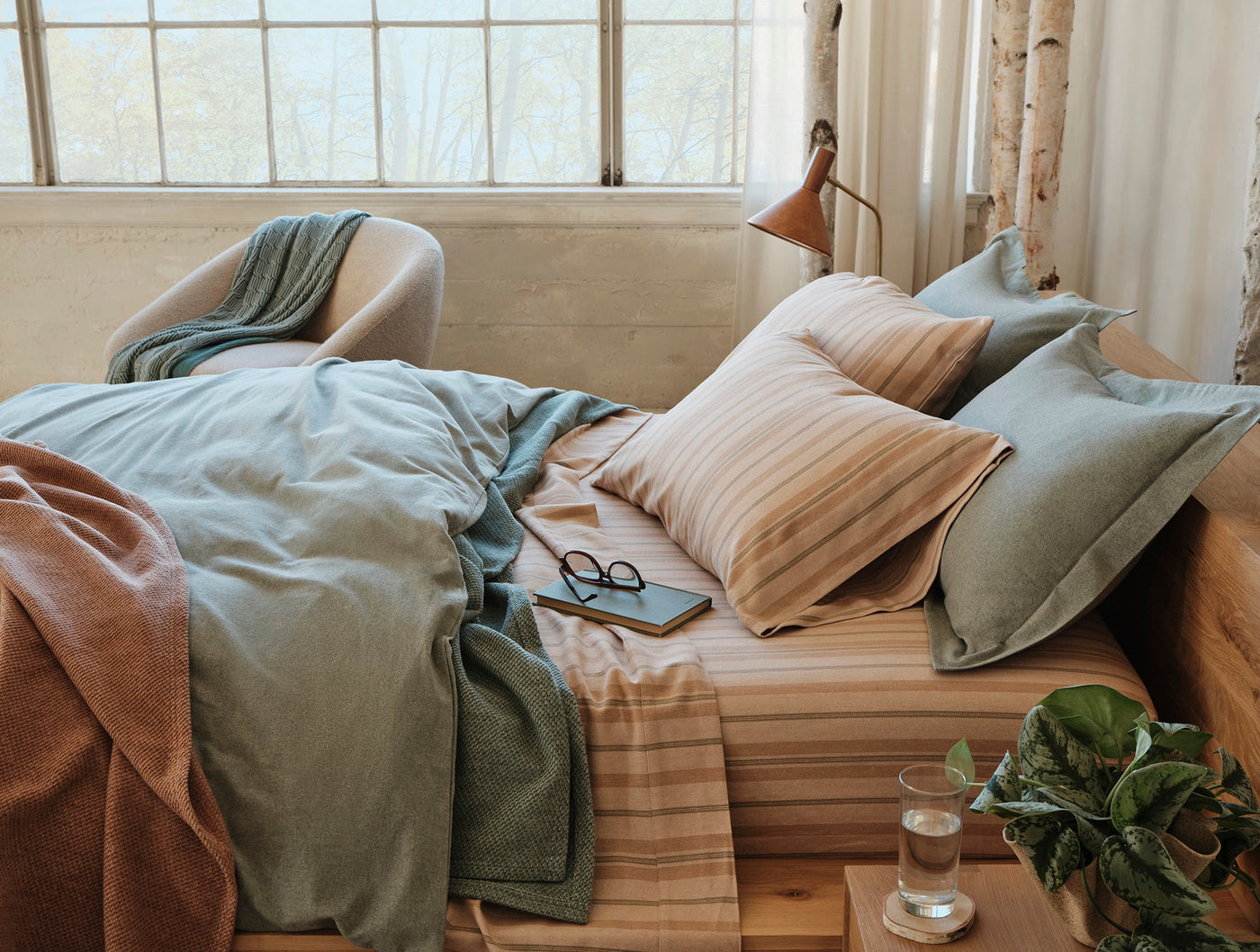 Sage green flannel sham styled on a layered bed with warm stripe bedding.