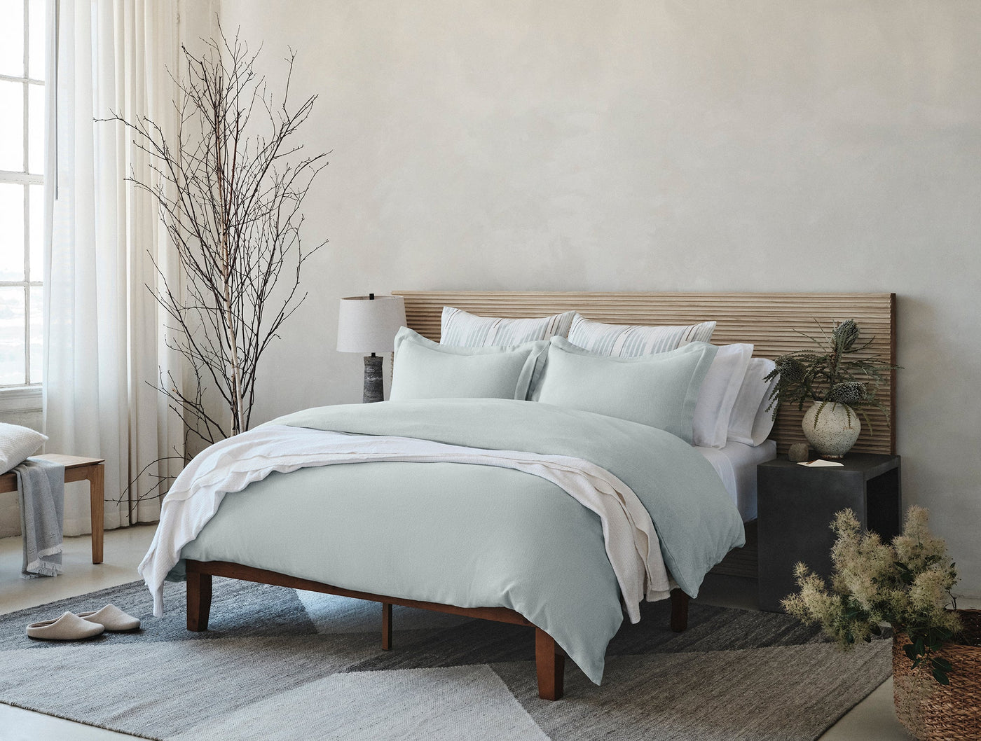 Pale sage flannel duvet and shams styled on a bed in a neutral, minimalist bedroom.