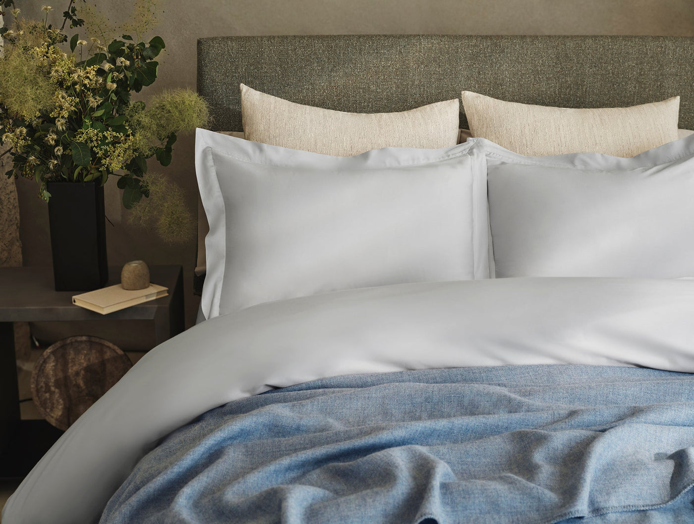 Pale blue alpaca throw draped across foot of bed styled with white bedding.