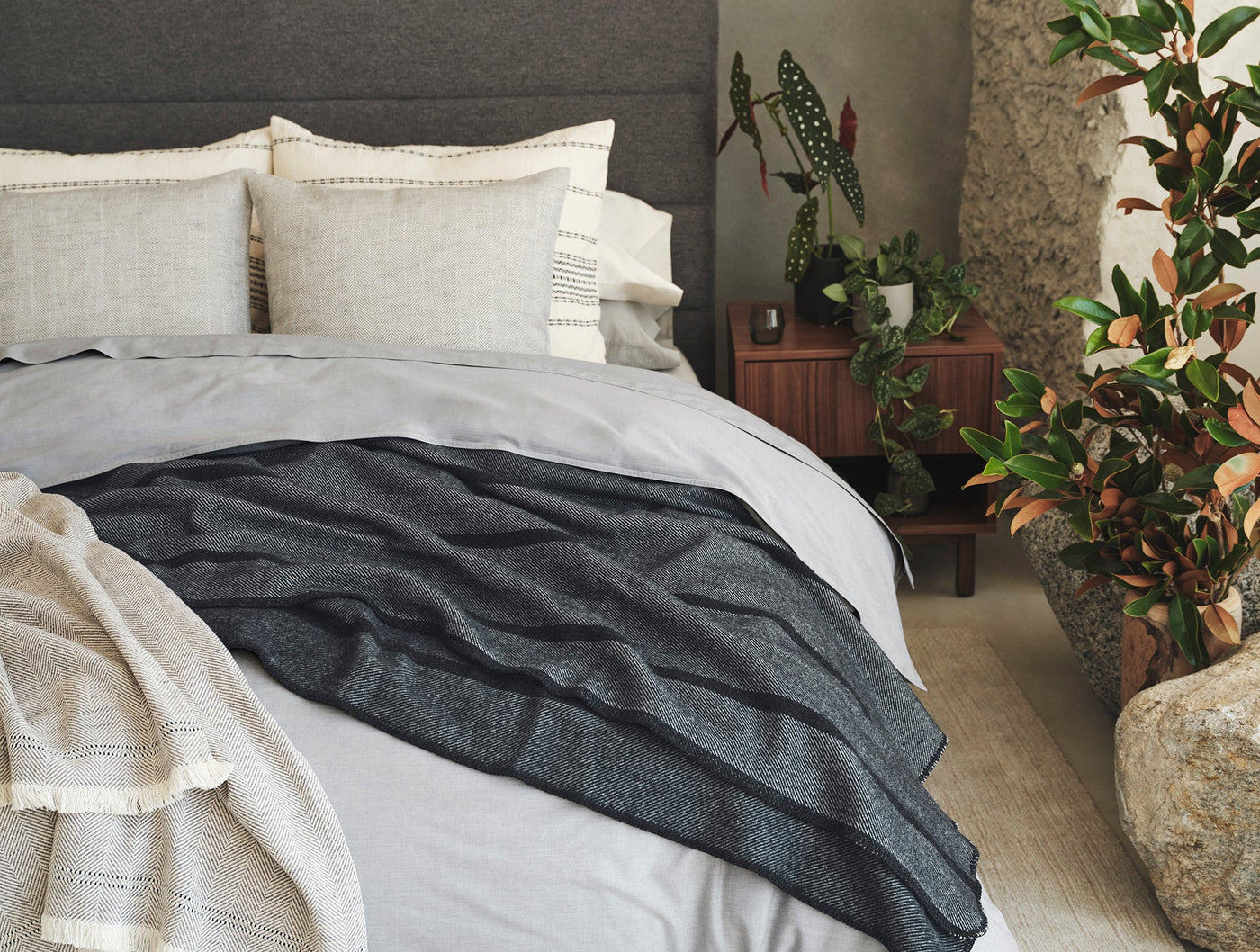 Coyuchi Crinkled Percale duvet cover in fog grey styled on a made bed with charcoal throw blanket.