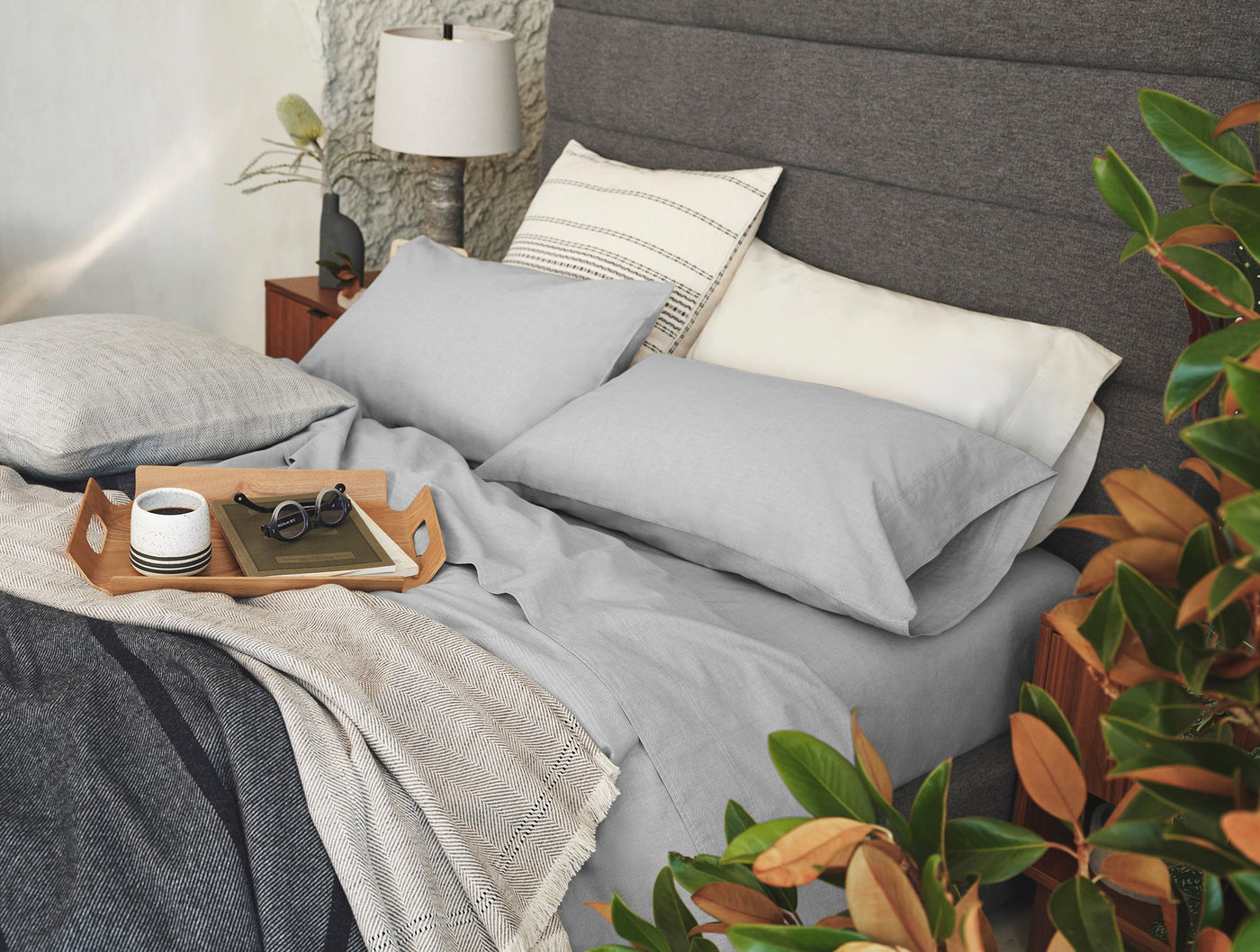 Coyuchi Crinkled Percale pillowcases in silver grey styled on a made bed.