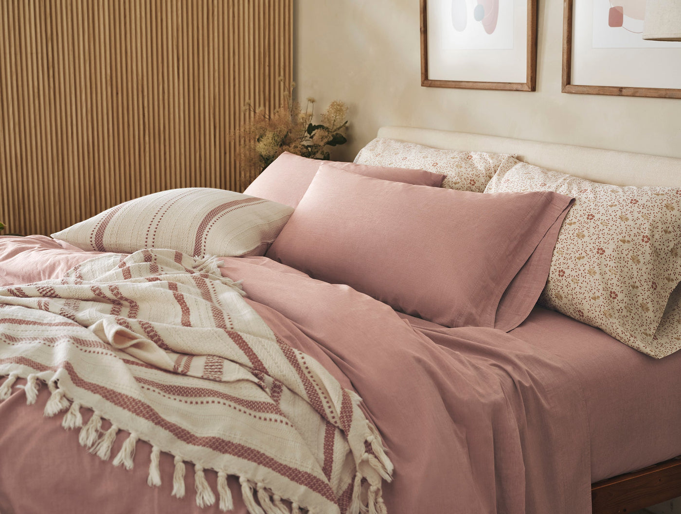 Dusty rose crinkled percale sheet set styled with floral pillows and a fringed throw.