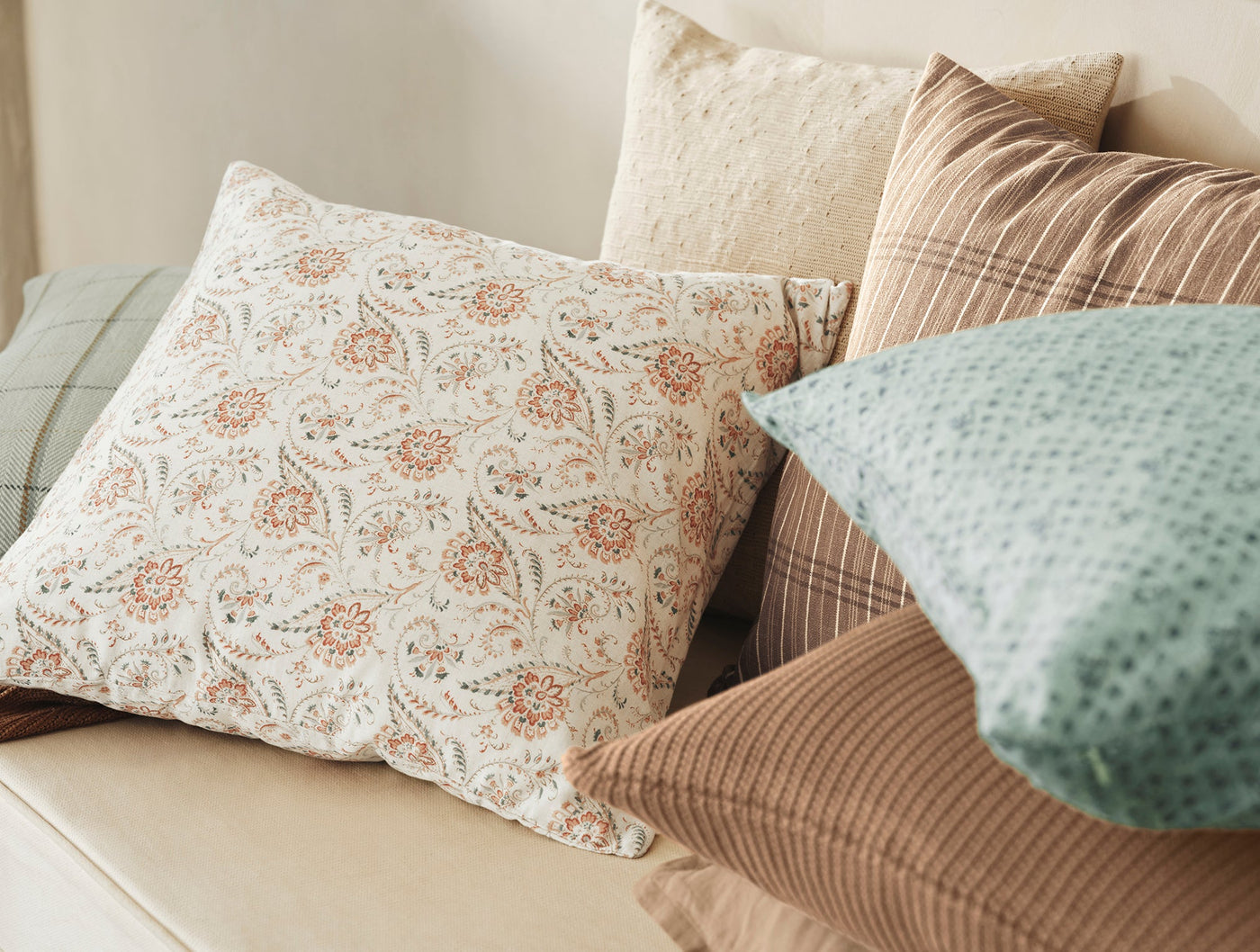Close-up of Coyuchi Ponderosa Print pillow among styled cushions in earth tones.