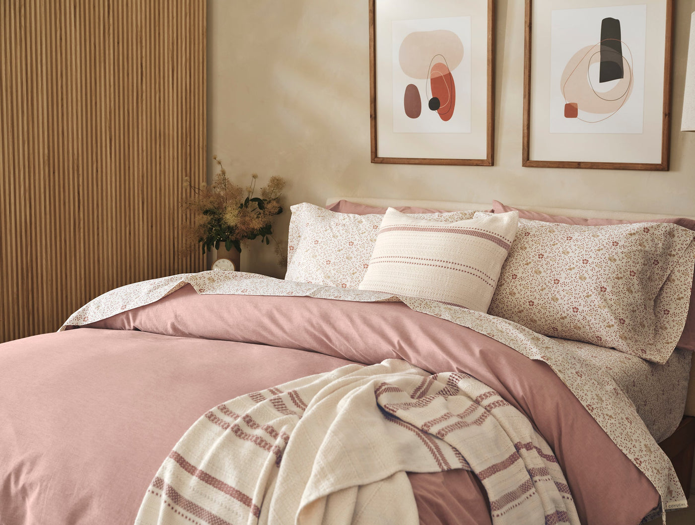Close-up of Coyuchi Crinkled Percale duvet cover in dusty rose, styled on a bed with floral pillows.