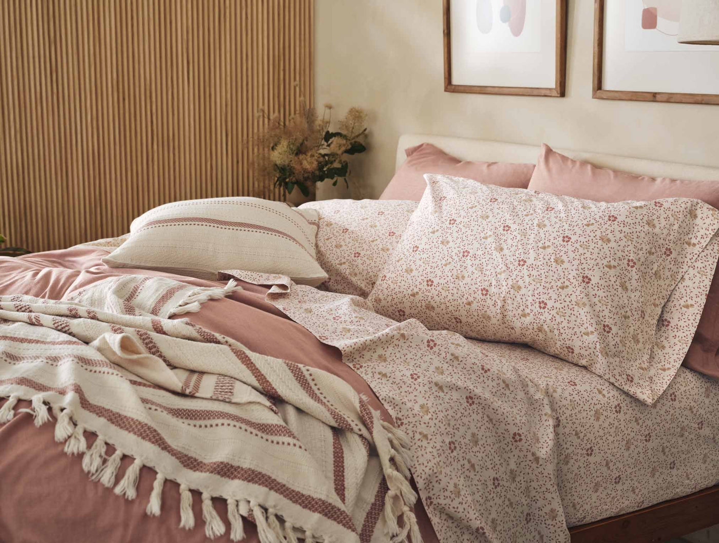 Close-up of Coyuchi Print Percale pillowcases in rose floral pattern on a styled bed.