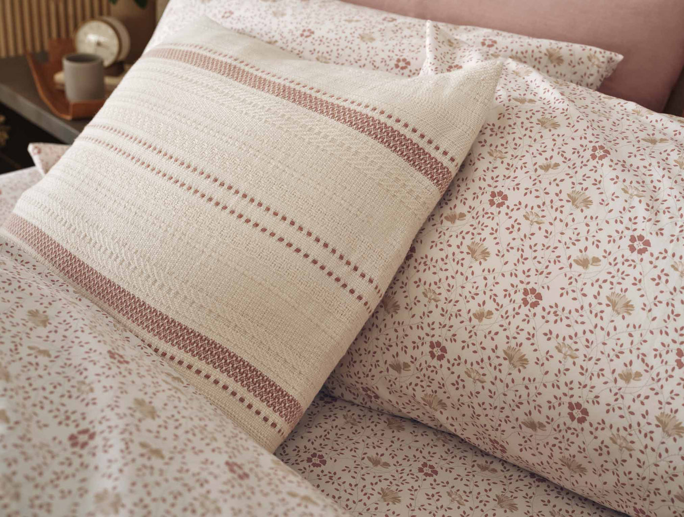 Close-up of Coyuchi Print Percale pillowcase with stripe detail alongside floral sheet set.