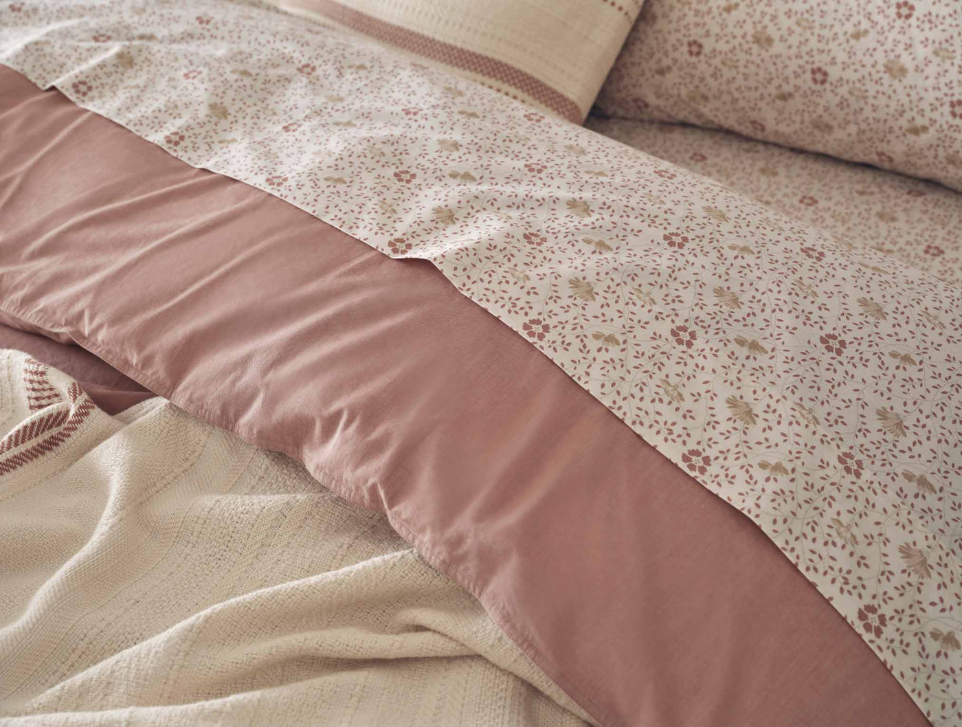 Close-up of dusty rose percale sheet set with delicate floral print and solid contrast panel.