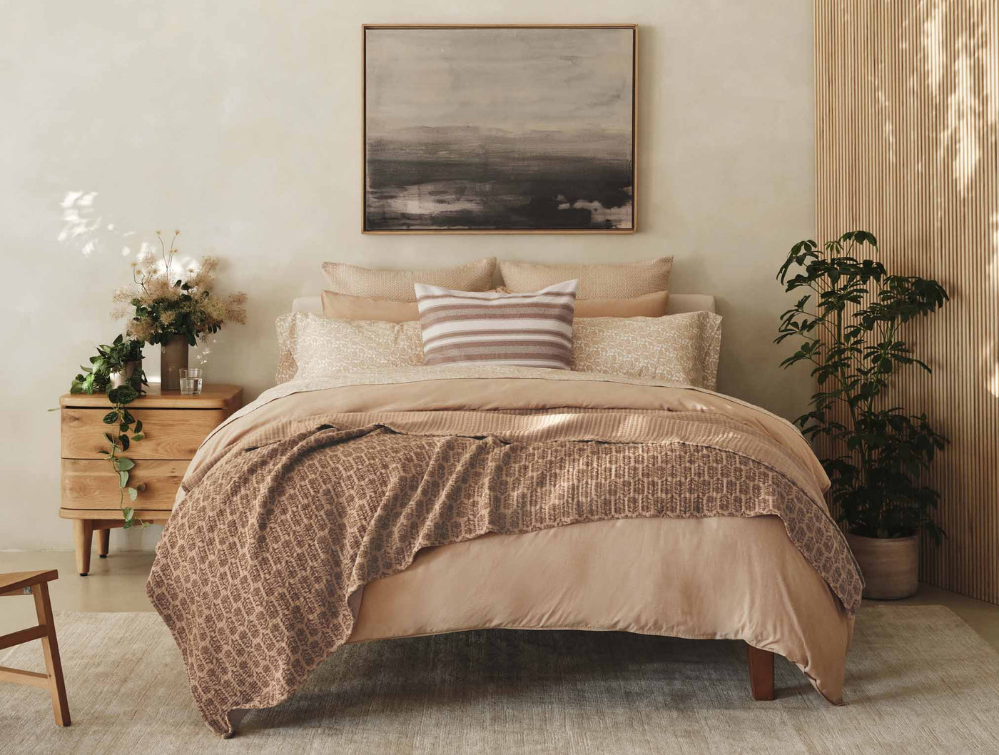 Warm-toned bedroom styled with Coyuchi percale bedding in blush, featuring geometric print throw.