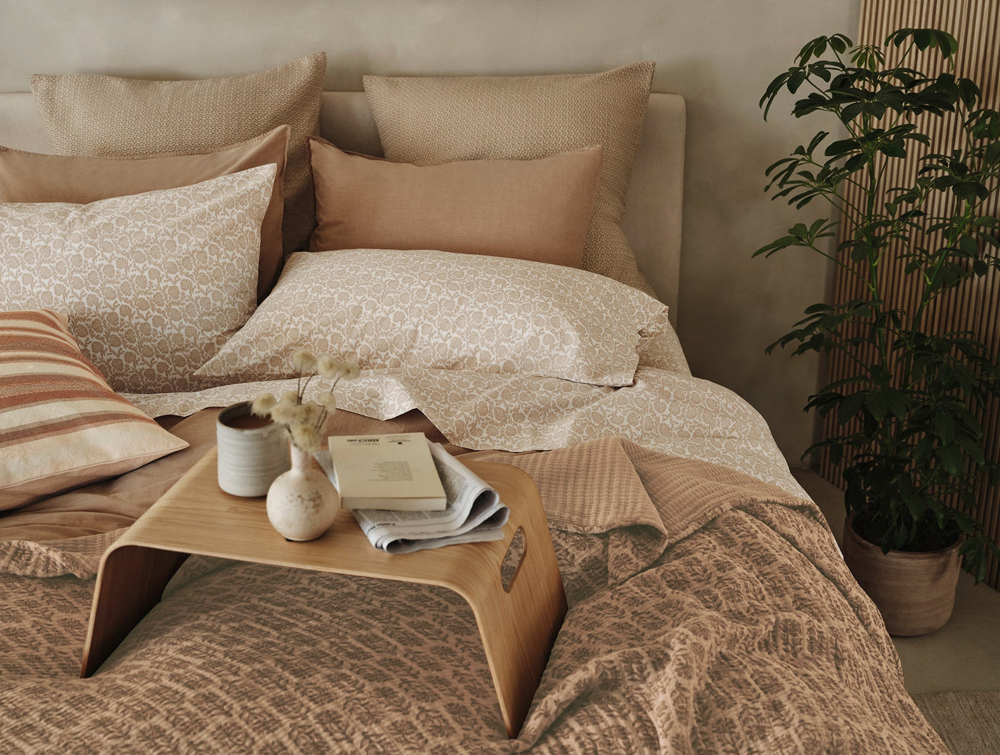 Caramel matelassé blanket with floral pattern draped over styled bed with layered neutral bedding.