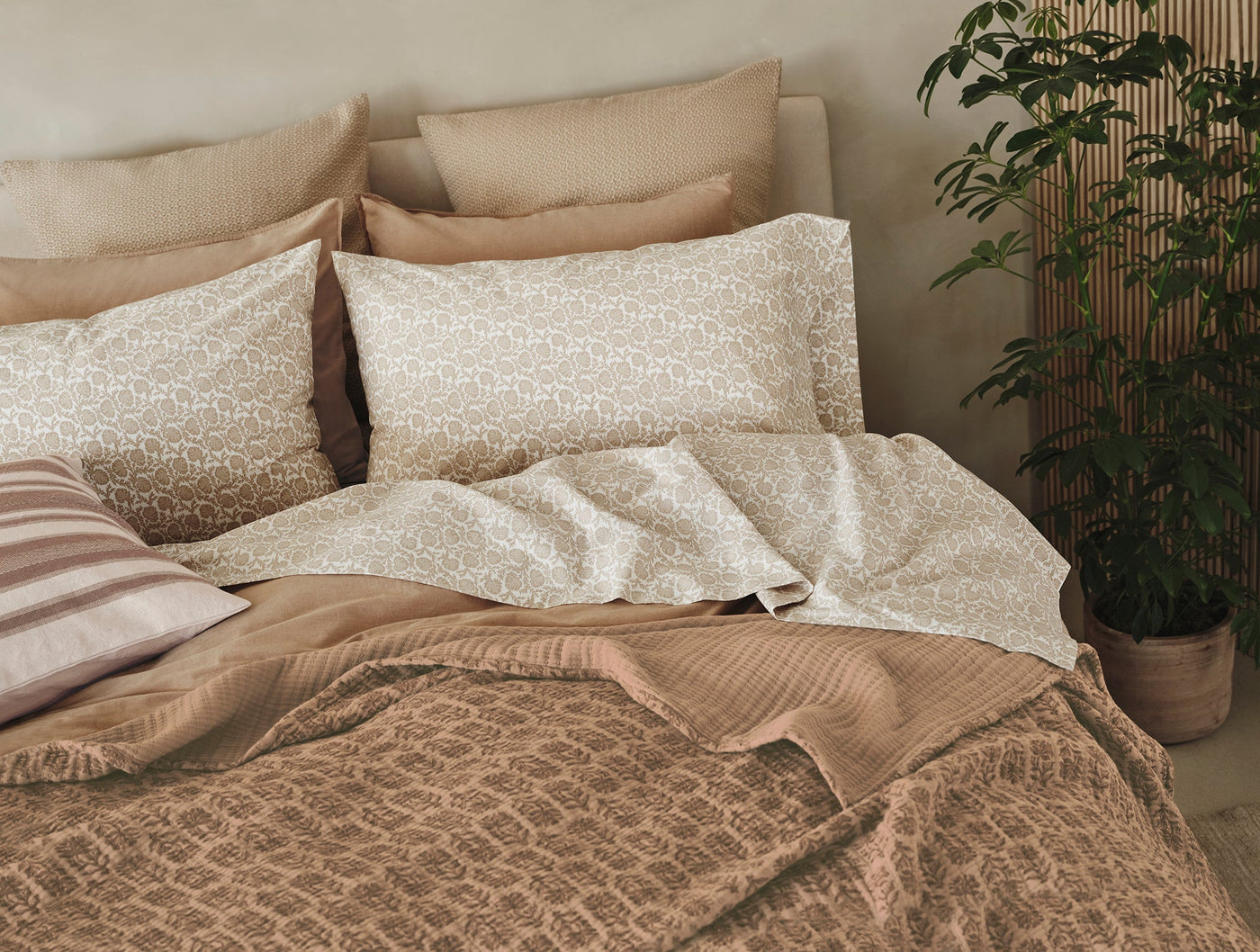 Coyuchi Mirada Matelasse blanket draped over styled bed with layered neutral bedding.