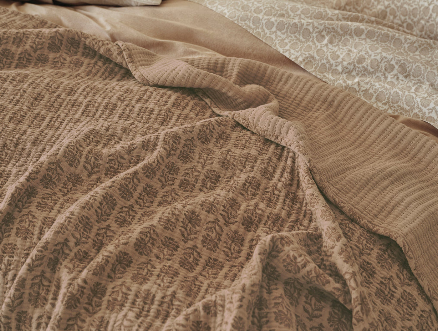 Close-up of Coyuchi Mirada Matelassé blanket in camel, showing botanical woven texture.