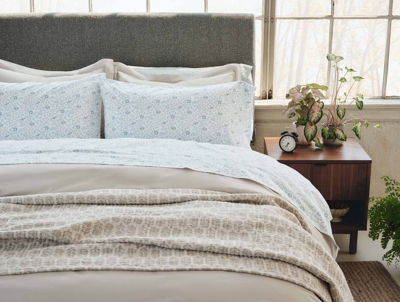 Coyuchi Print Percale pillowcases in pale blue floral pattern styled on a made bed.