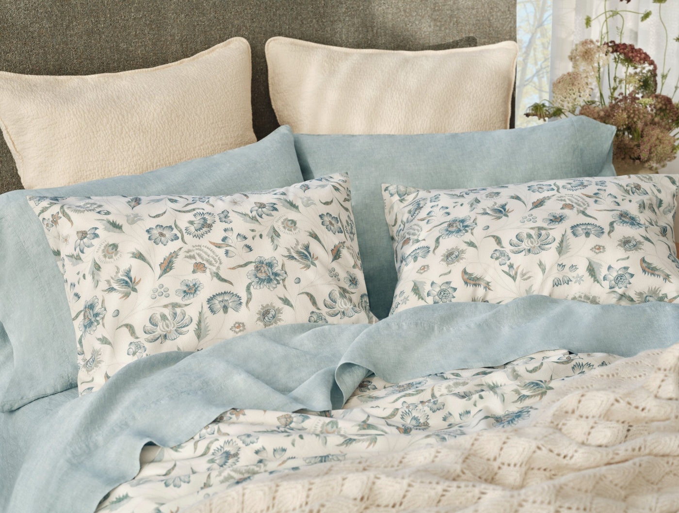Close-up of Coyuchi Viola Print sham in ivory with blue floral botanical pattern, linen border.